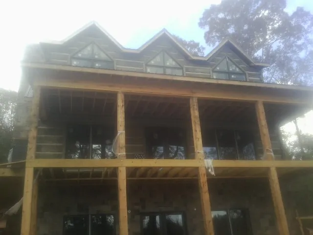 Dormers and porch framing on a large log home under construction — Roof Coating work by our crew in Uncasville