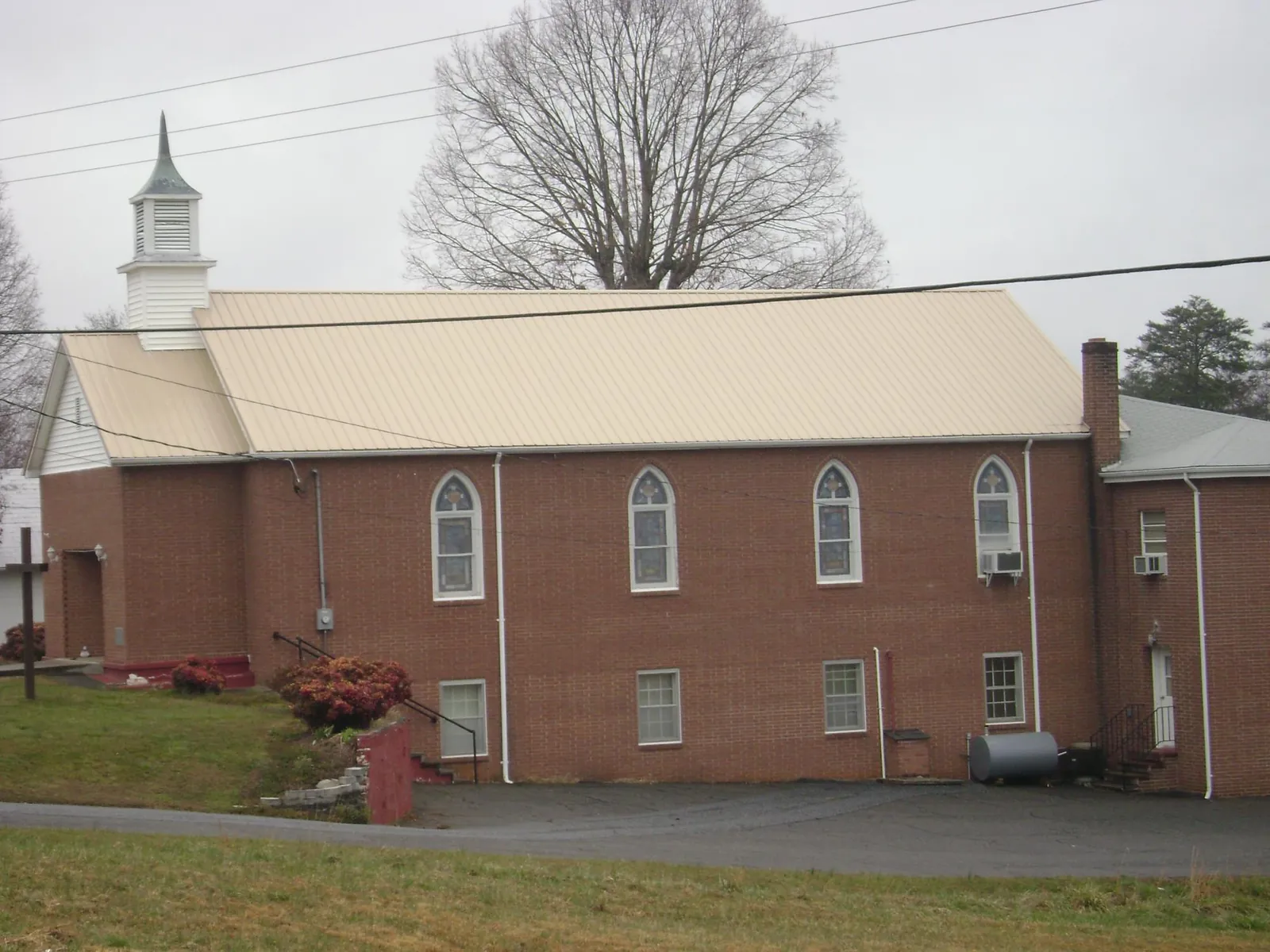 New tan metal roof on a brick church with a white steeple in Uncasville