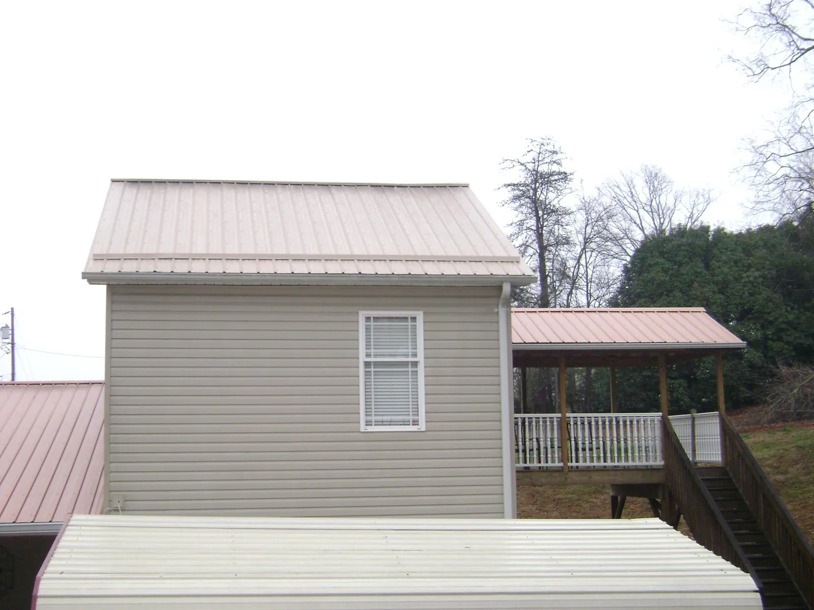 Tan metal roofs on a two story addition and attached porch, from a Roof Replacement job in Uncasville