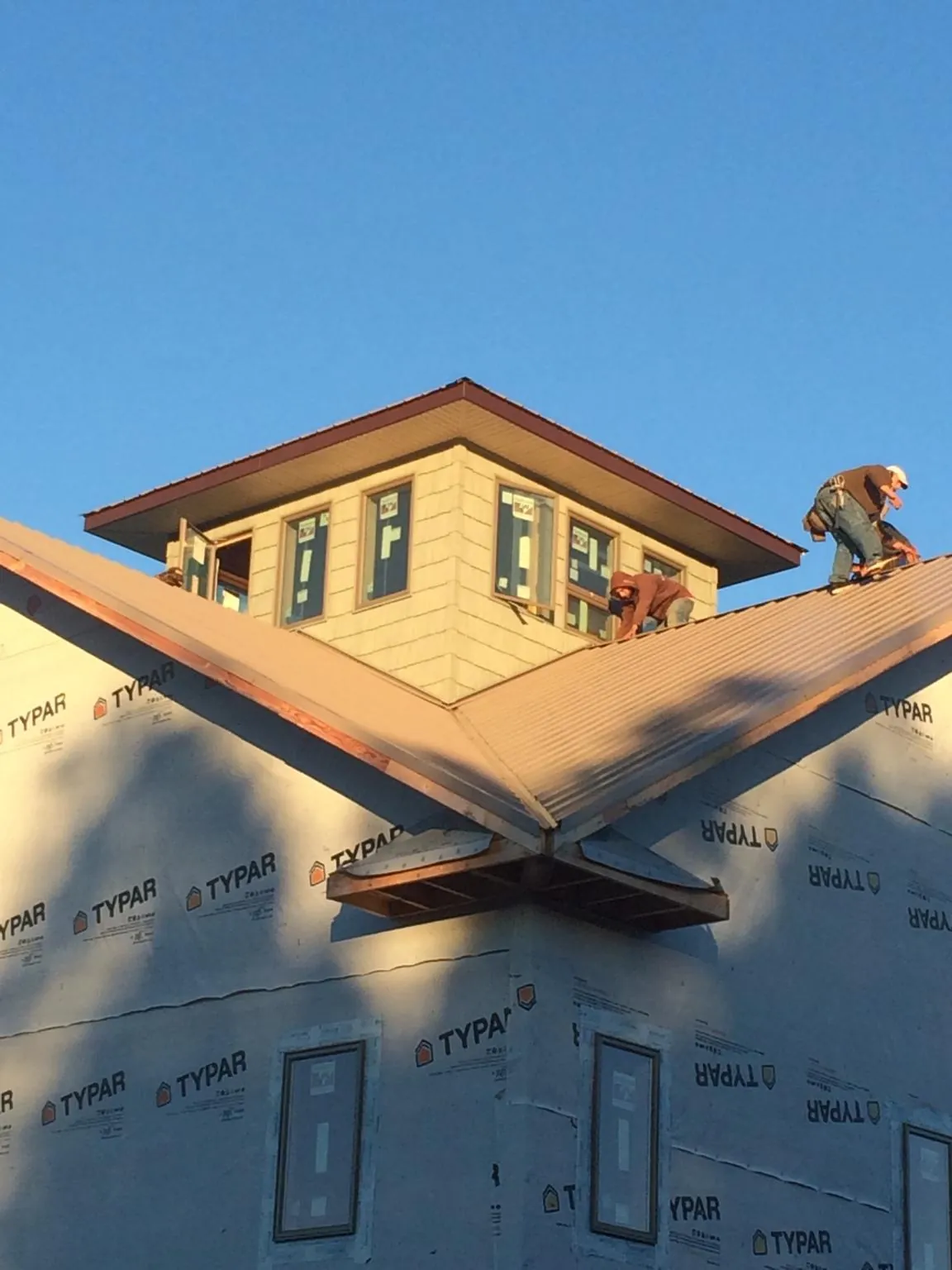 Roofers working around a rooftop cupola on a new metal roof at sunset — Roof Waterproofing in Uncasville by Roofing Brothers